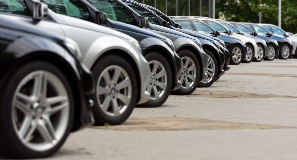 Row of parked cars at dealership.