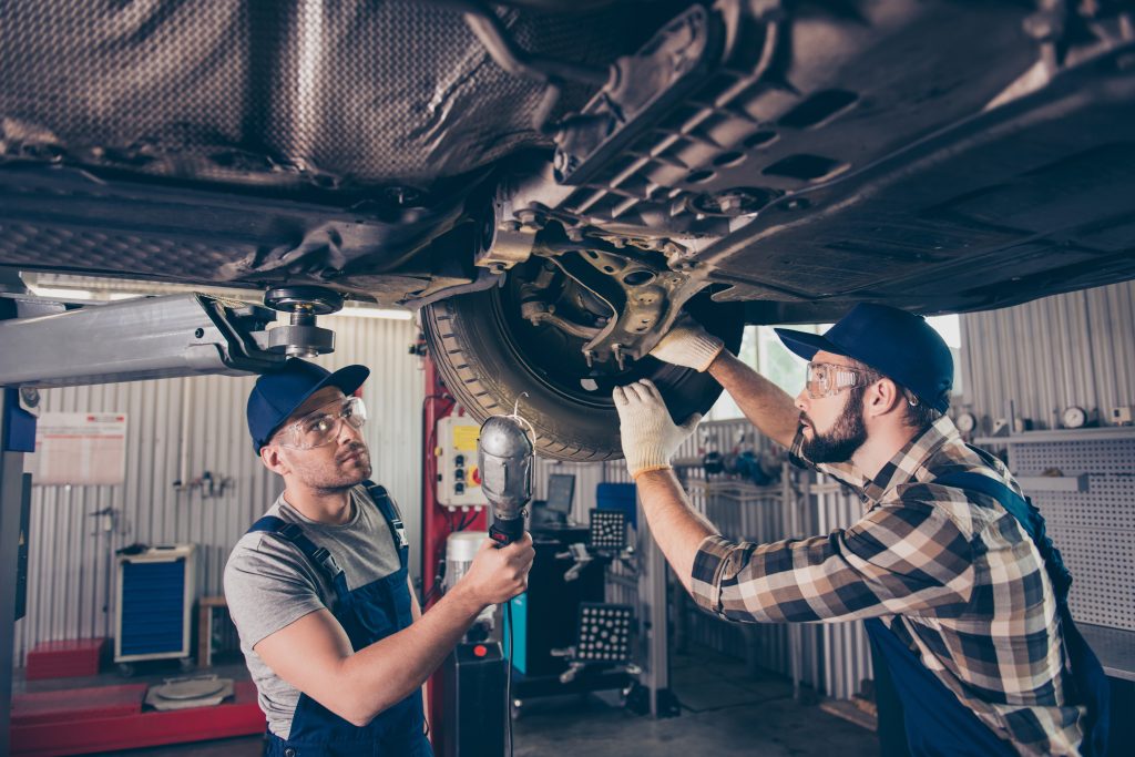 Mechanics inspecting a car on a service lift.