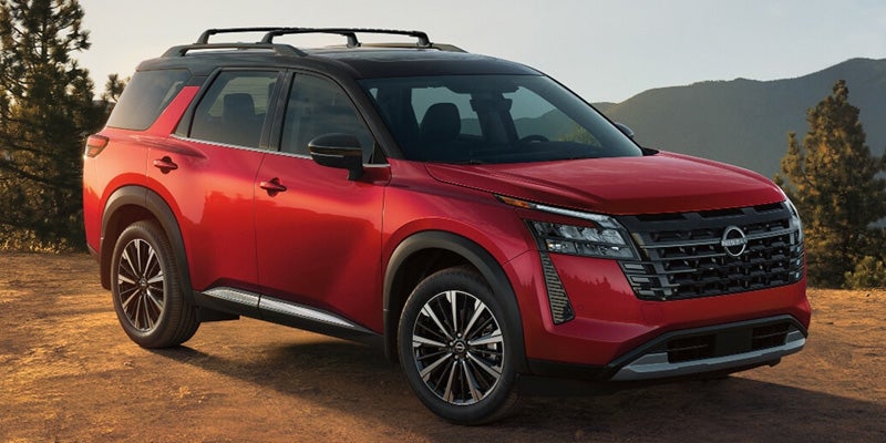 A red Nissan Pathfinder SUV parked in a mountainous outdoor setting.