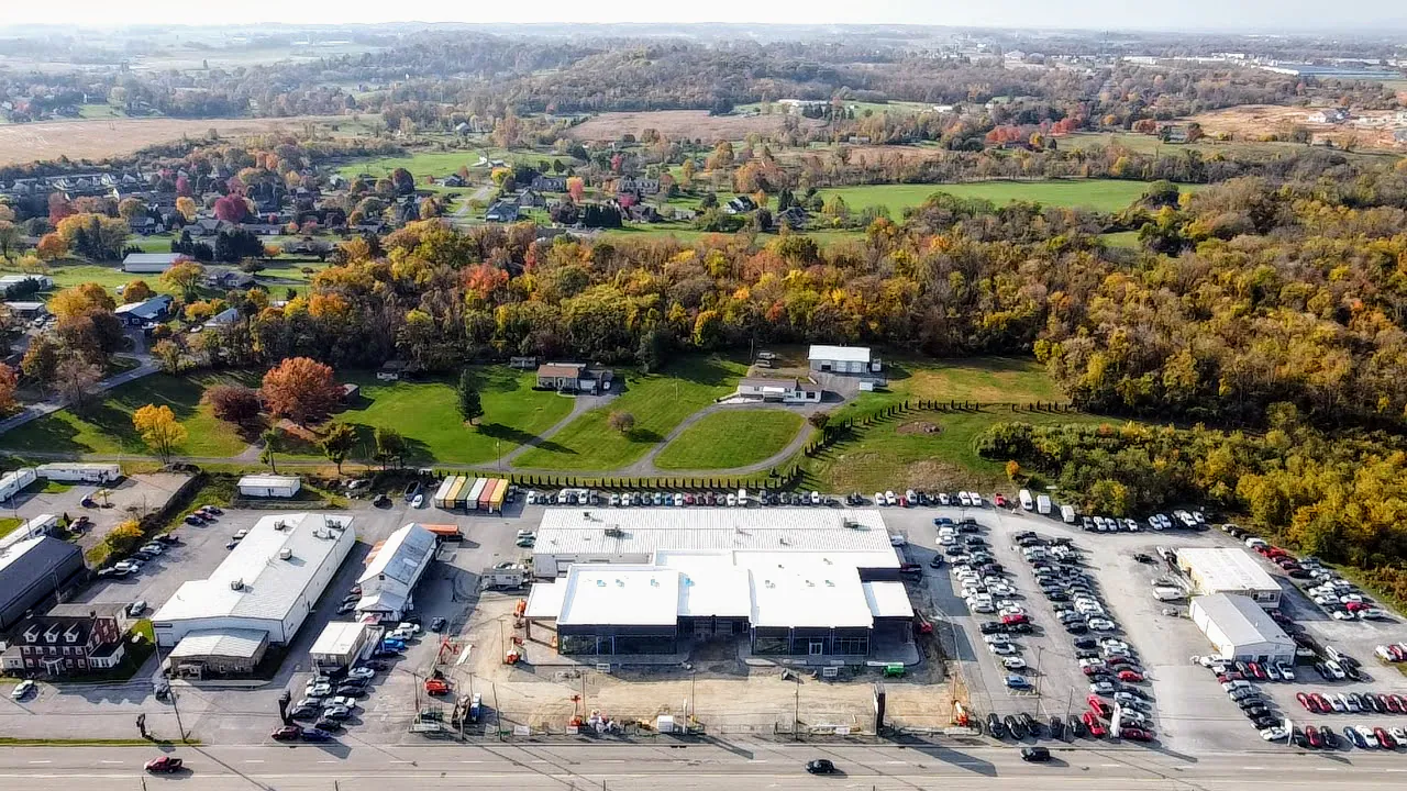 Aerial view of a car dealership surrounded by trees and countryside in autumn.