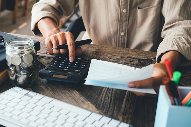 Man budgeting with calculator and coins on desk
