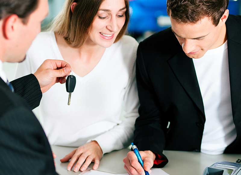 Smiling couple getting new car keys at showroom