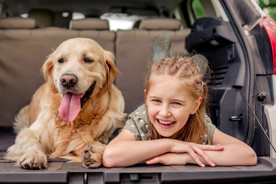 Girl sitting with a dog at the back of a car