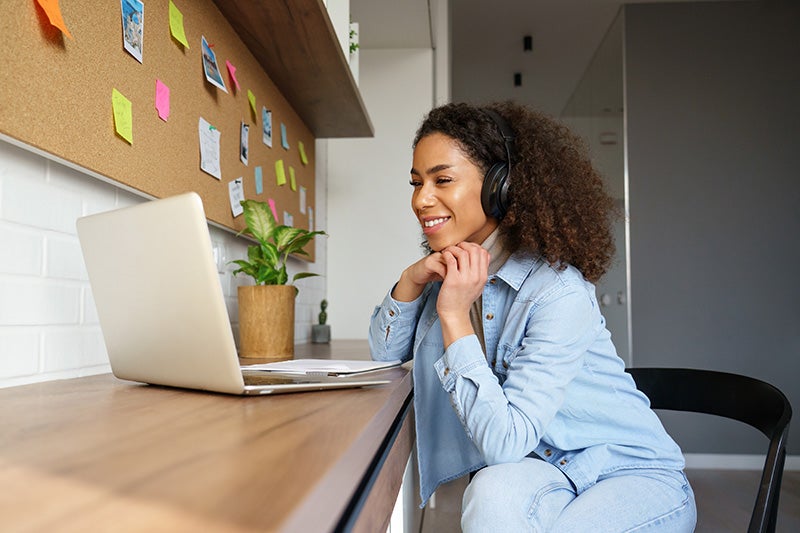 Woman smiling while sitting in front of a laptop